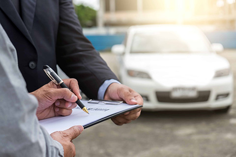 Independent agent and client reviewing a claim in front of car